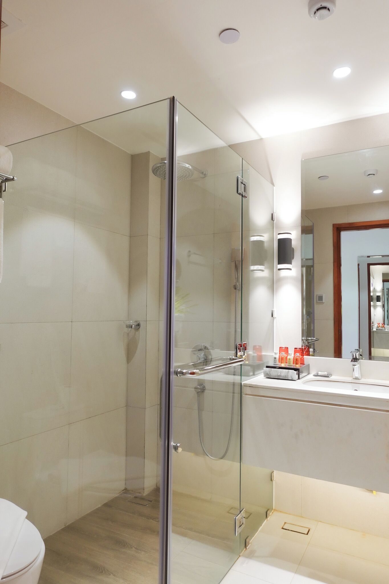 A modern bathroom with a glass-enclosed shower, a toilet, and a vanity with a mirror.