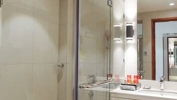 A modern bathroom with a glass-enclosed shower, a toilet, and a vanity with a mirror.