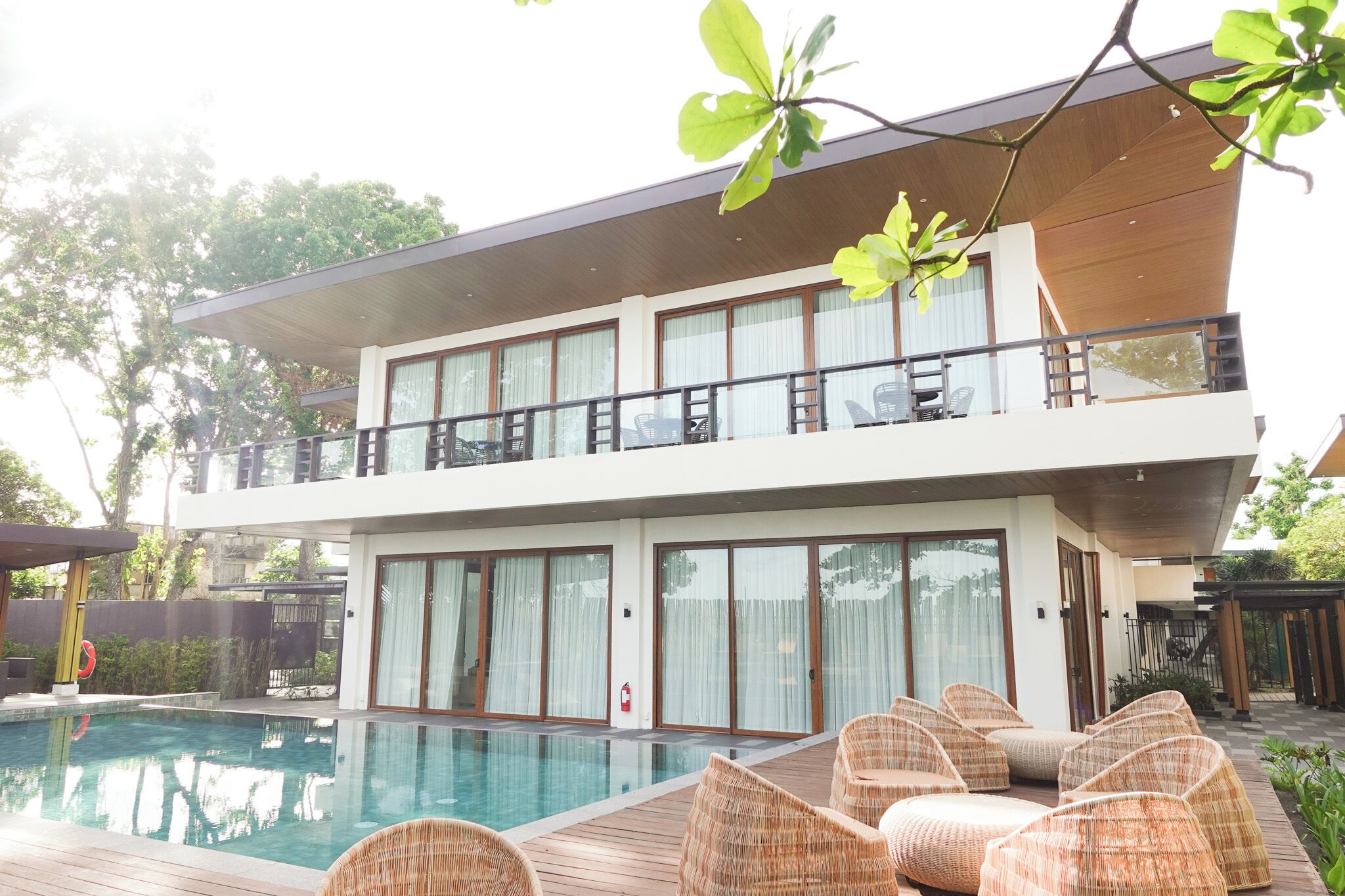 A two-story building with a pool, outdoor seating, and a covered area.