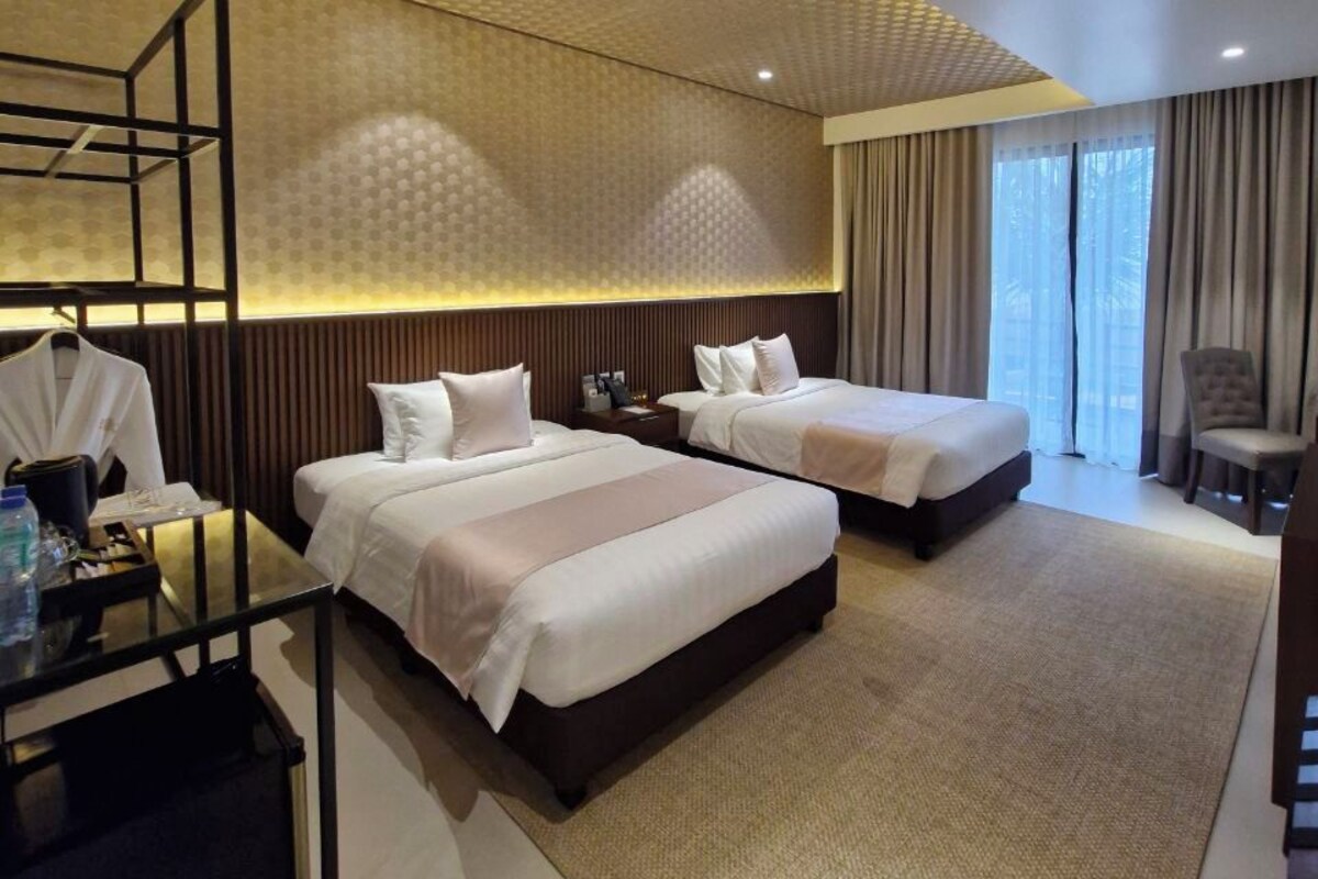 Ein Hotelzimmer mit zwei Betten, einem Schreibtisch, einem Stuhl und einem Kleiderschrank.