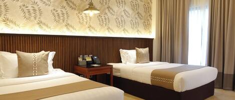 A hotel room with two beds, a wooden headboard, a nightstand with a phone, and a patterned wall.