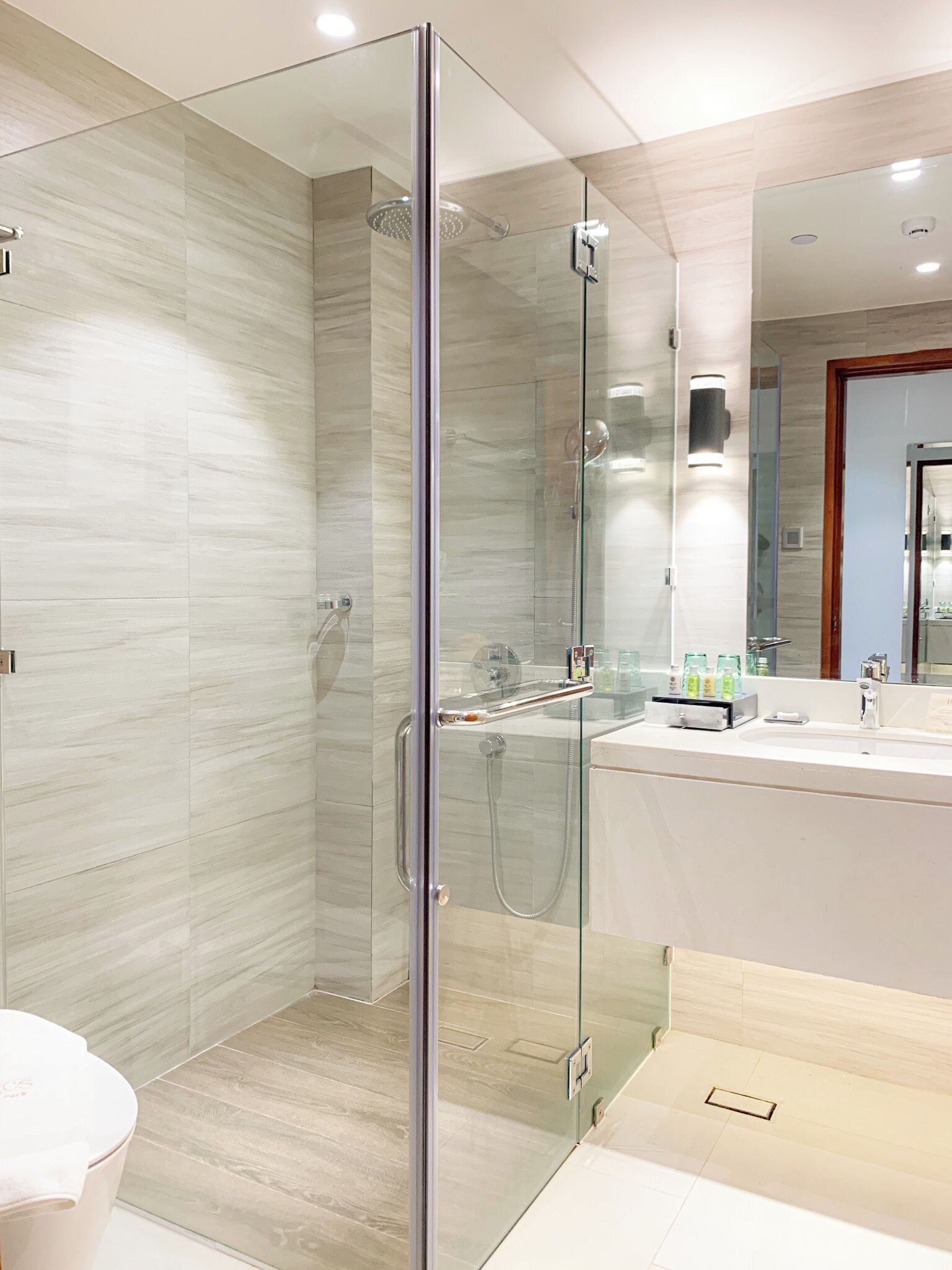 Un baño moderno con ducha envuelta en vidrio, tocador con espejo y un inodoro.