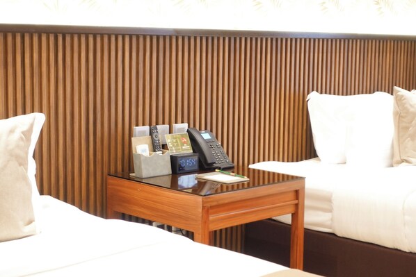 A hotel room with a wooden panel wall, a desk with a telephone, a notepad, and a pen. - The Tropics at MacArthur Park Resort and Convention Center (Palo)