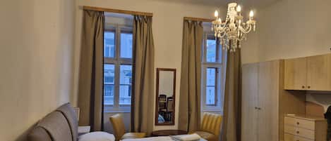 Une chambre à coucher comprenant un lit, deux chaises, un miroir, un lustre et une armoire.
