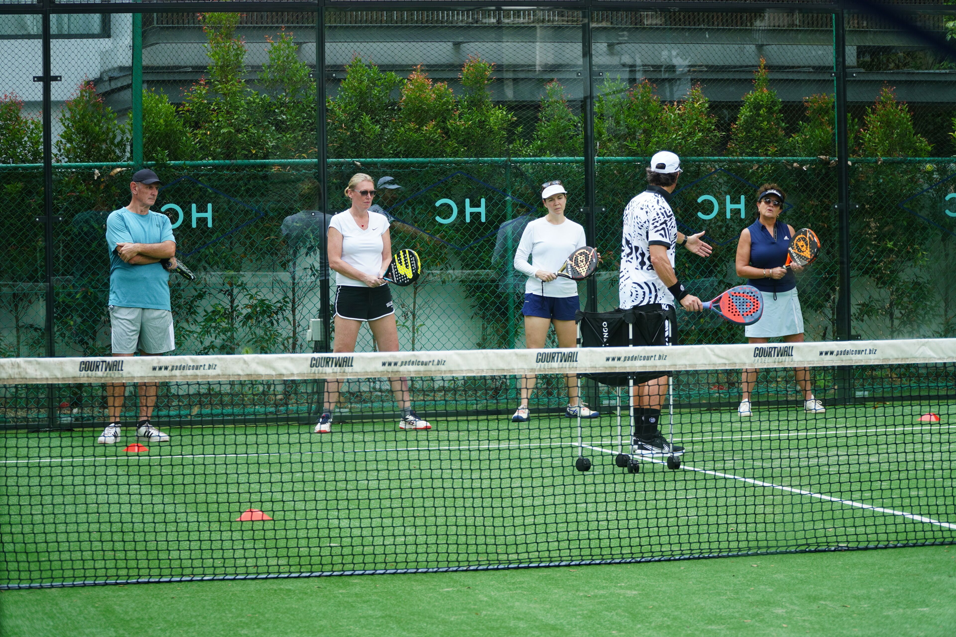 Un court de tennis avec des joueurs et un entraîneur.