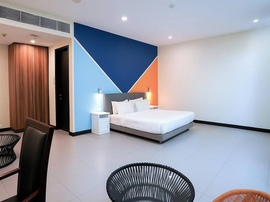 Een moderne hotelkamer met een bed, nachtkastjes, een stoel en een zithoek met tafel en stoelen.