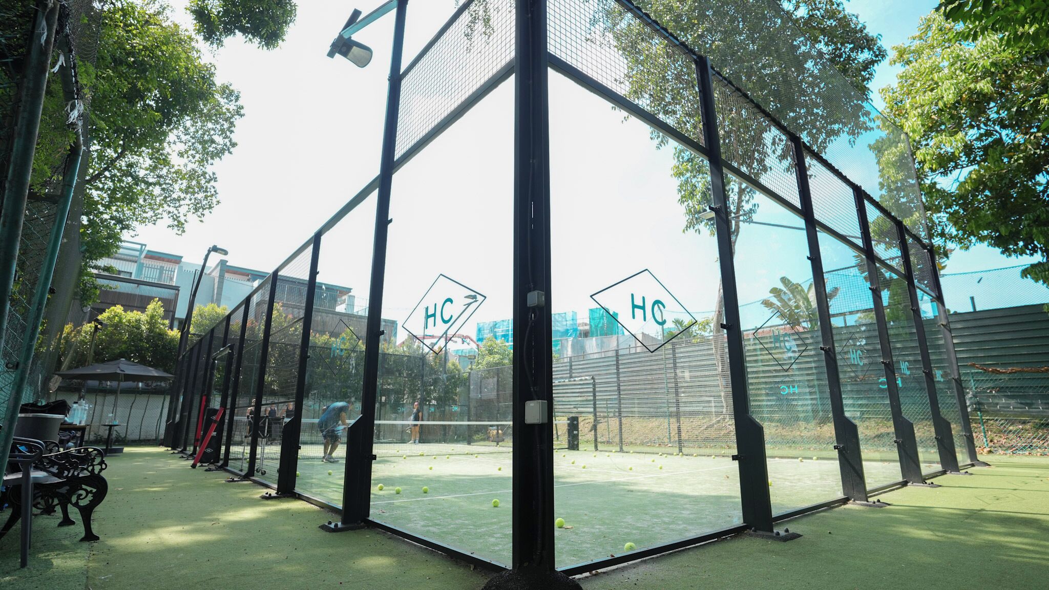 Una cancha de tenis con red y un cartel que dice 'HC'.