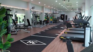 Un gimnasio con cintas de correr, máquinas de pesas y un muro de espejos.