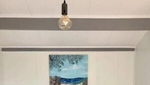 Ein blaues Sofa in einem Raum mit einer weißen Wand und einem Landschaftsbild.