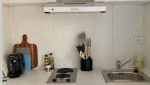 Eine kleine Küchenzeile mit Herd, Spüle und Staukästen.