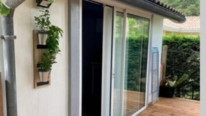 Ein modernes Gebäude mit einer Holzdachterrasse, großen Schiebeg lassüren und einer Metallrohrleitung an der Außenwand.