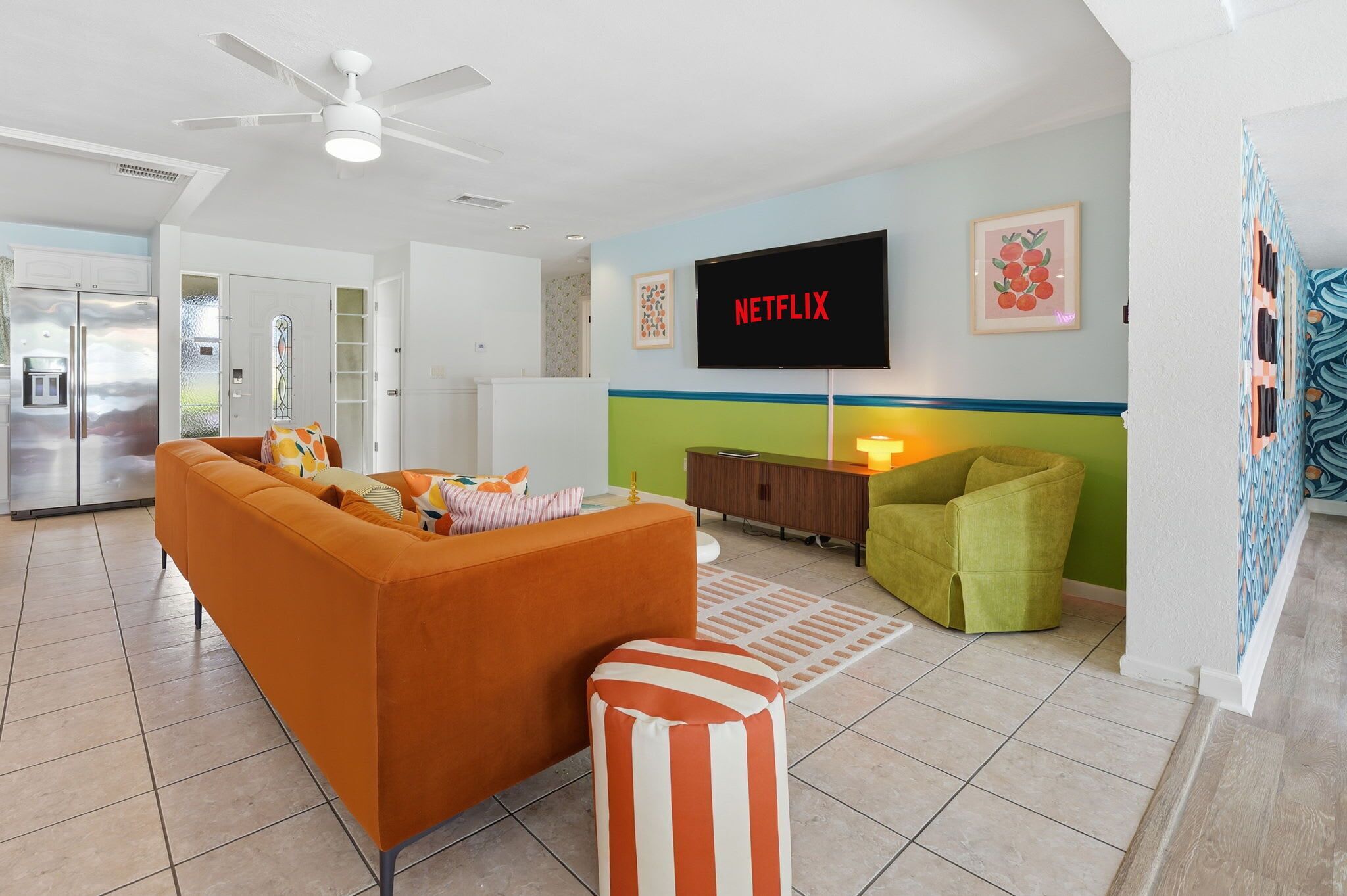 A modern living room with a sofa, ottoman, and a television mounted on the wall.