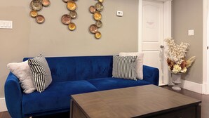 Un sofá azul con almohadones estampados, una mesa de centro de madera y decoración en la pared.