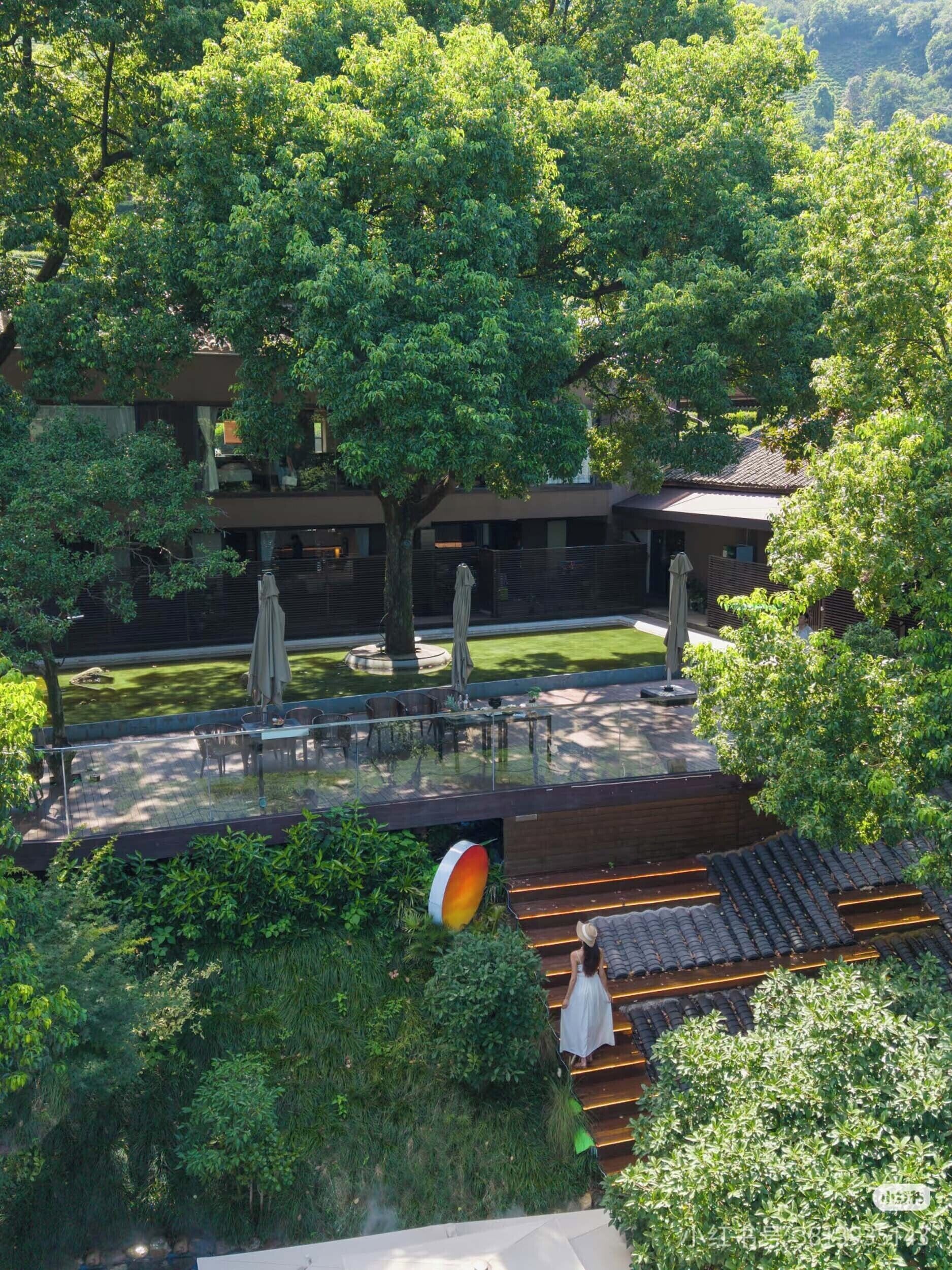 A rooftop terrace with a koi pond, outdoor seating, and a view of surrounding greenery.