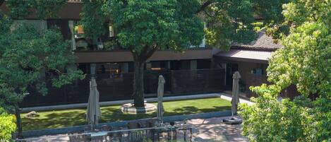 A rooftop terrace with a koi pond, outdoor seating, and a view of surrounding greenery.