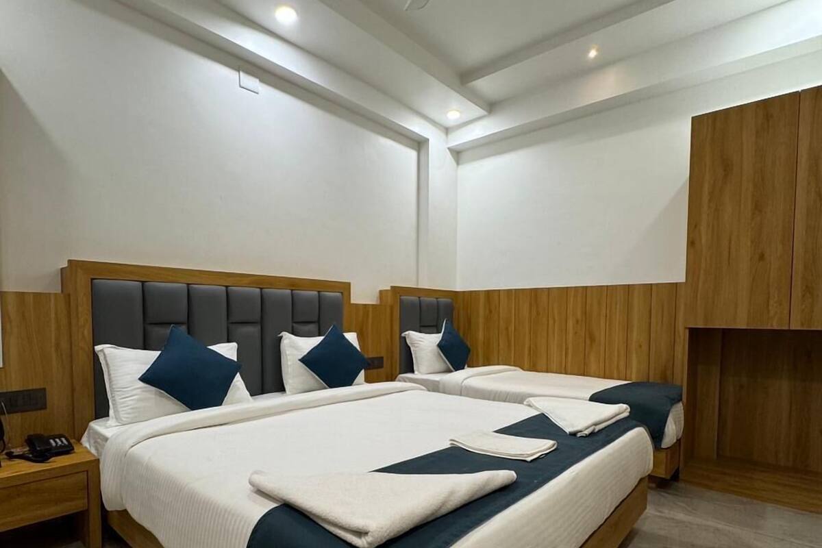 A modern hotel room with a large bed, wooden headboard, and a ceiling fan.