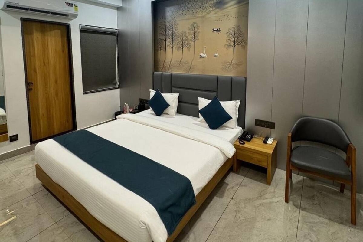 A modern bedroom with a large bed, a ceiling fan, a painting of swans, and a wooden door.
