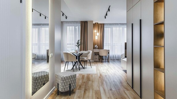 Una habitación de hotel moderna con suelo de madera, un área de comedor con mesa y sillas, y un armario grande.
