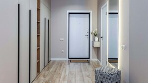Un pasillo con suelo de madera, un banco y una puerta al final.