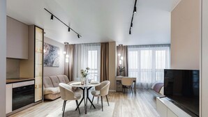 Una sala de estar moderna con comedor, cocina y televisor.