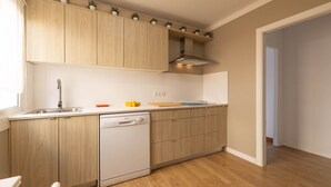 A kitchen with wooden cabinets, a dishwasher, and a window. - Sol y Mar by Rentallorca (Can Picafort)