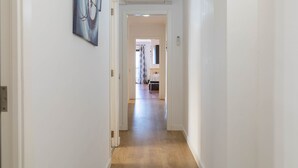 A hallway with a wooden floor, white walls, and a ceiling-mounted air conditioner. - Sol y Mar by Rentallorca (Can Picafort)