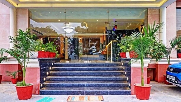 A hotel entrance with a glass facade, marble steps, and potted plants. - Hotel Green View (Agra)