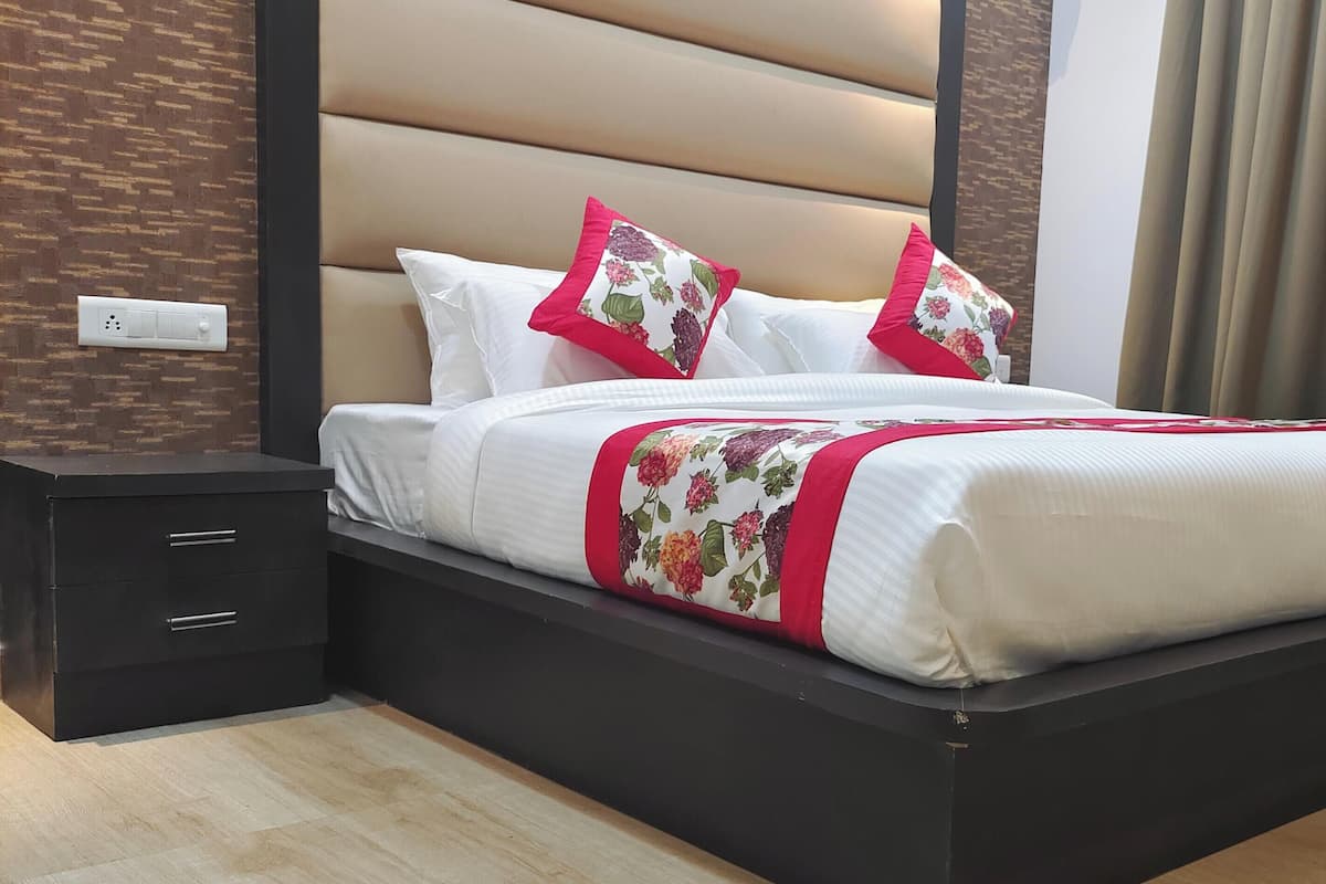 Habitación de hotel moderna con una cama grande, una mesita de noche y un enchufe en la pared.