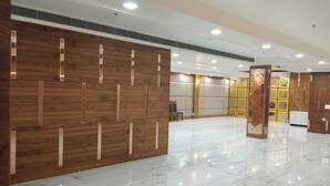 A spacious lobby with a polished marble floor, wooden paneling with vertical accents, and a seating area with chairs and a table. - Hotel Green View (Agra)
