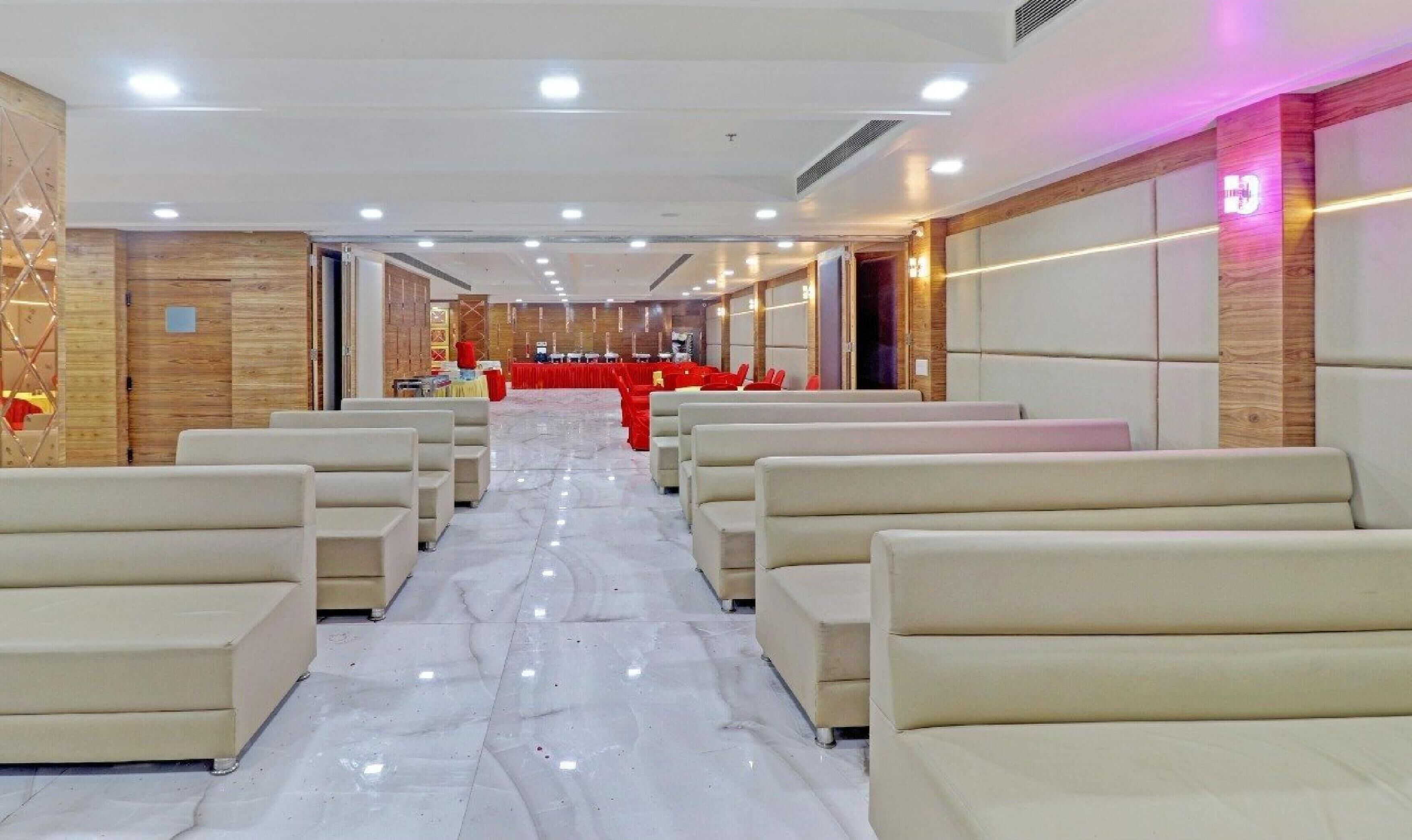 A hotel lobby with rows of beige sofas, a marble floor, and wooden paneling on the walls.