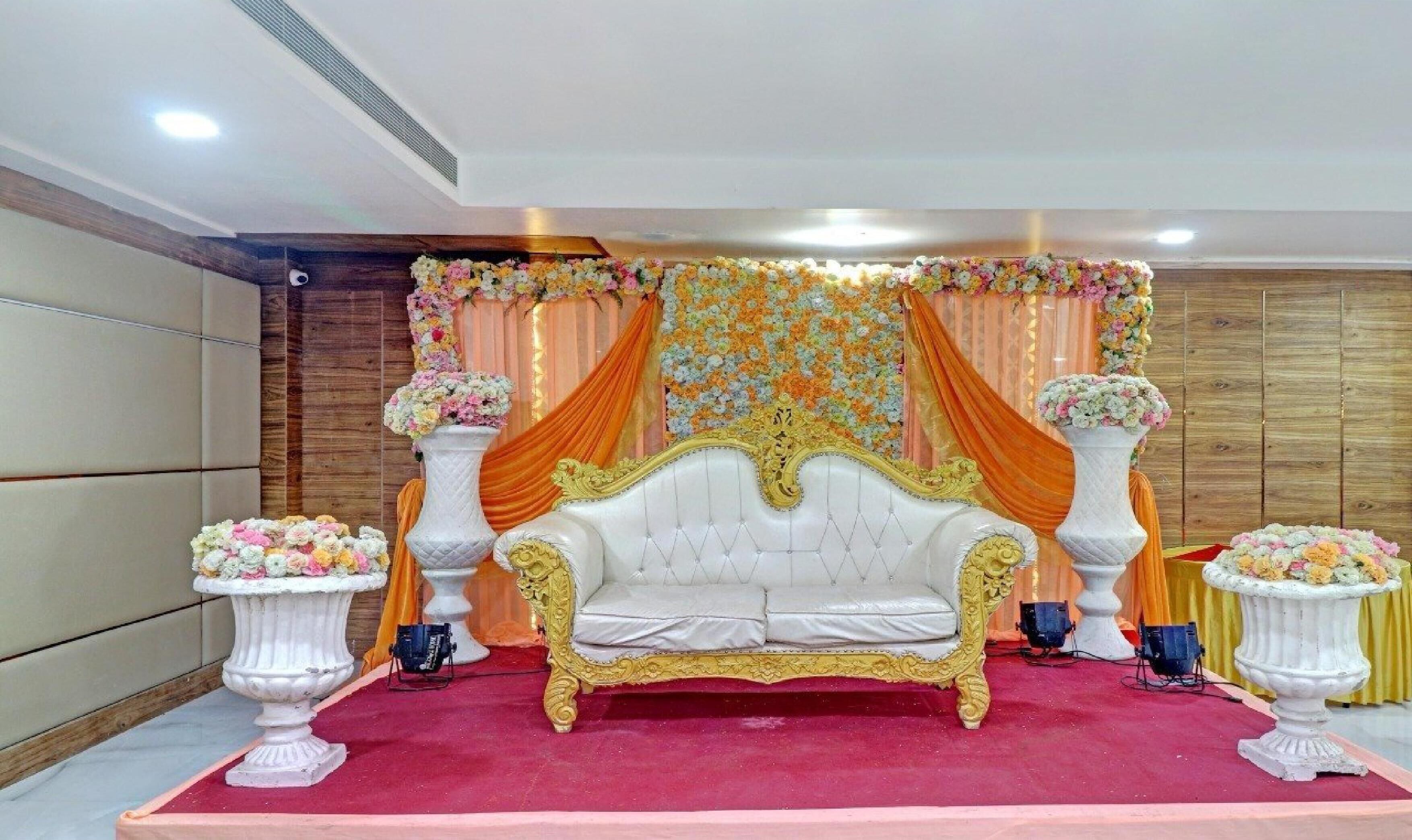 Ein luxuriöses Zimmer mit einer weißen, verzierten Couch, floralen Arrangements und Vorhängen.