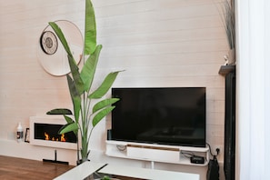 Uma sala de estar moderna com uma TV de tela plana, uma lareira e uma planta grande.
