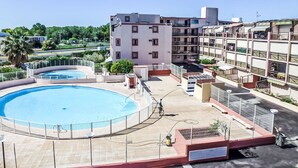 A residential building with a swimming pool, a covered outdoor area, and a view of the surrounding landscape.