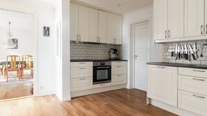 Et moderne køkken med hvide skabe, en sort bordplade og trægulv.