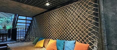 A room with a woven bed, a geometric ceiling, and a view of the outdoors.