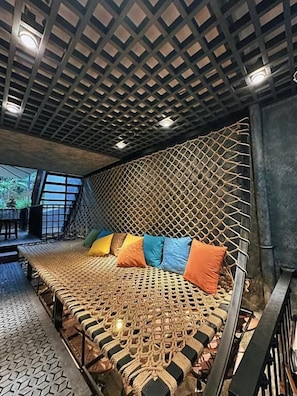A room with a woven bed, a geometric ceiling, and a view of the outdoors.