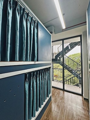 A room with a staircase leading to a balcony, a window with curtains, and a wooden floor.