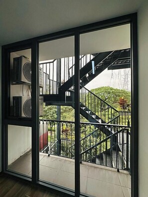 A room with a large window, a staircase, and an air conditioning unit. - AMANGO HOME BRAND 5 (Ho Chi Minh City)