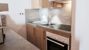 Uma cozinha compacta com pia dupla, eletrodomésticos de aço inoxidável e armários de madeira.