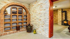 Una habitación con chimenea de ladrillo, pared de piedra y una estantería de madera para vinos.