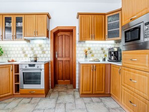 Een koelkast, een oven, een vaatwasser, kookgerei, borden en bestek