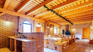 Una cocina rústica con vigas de madera a la vista, paredes de ladrillo y una isla central con asientos.