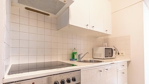 A kitchen with white tiles, a stove, a microwave, and a sink. - Affordable Cozy 2BR Apt Near Stadthalle (Vienna)