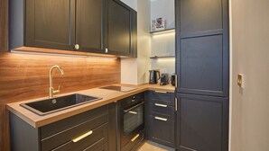 A modern kitchen with dark cabinets, a wooden countertop, a sink, and built-in appliances. - Eiffel Tower Apartment Invalides (Paris)