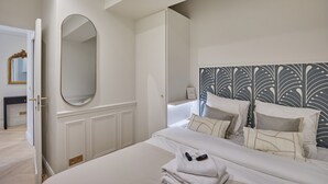 A hotel room with a large bed, a mirror, a wardrobe, and a decorative headboard. - Eiffel Tower Apartment Invalides (Paris)