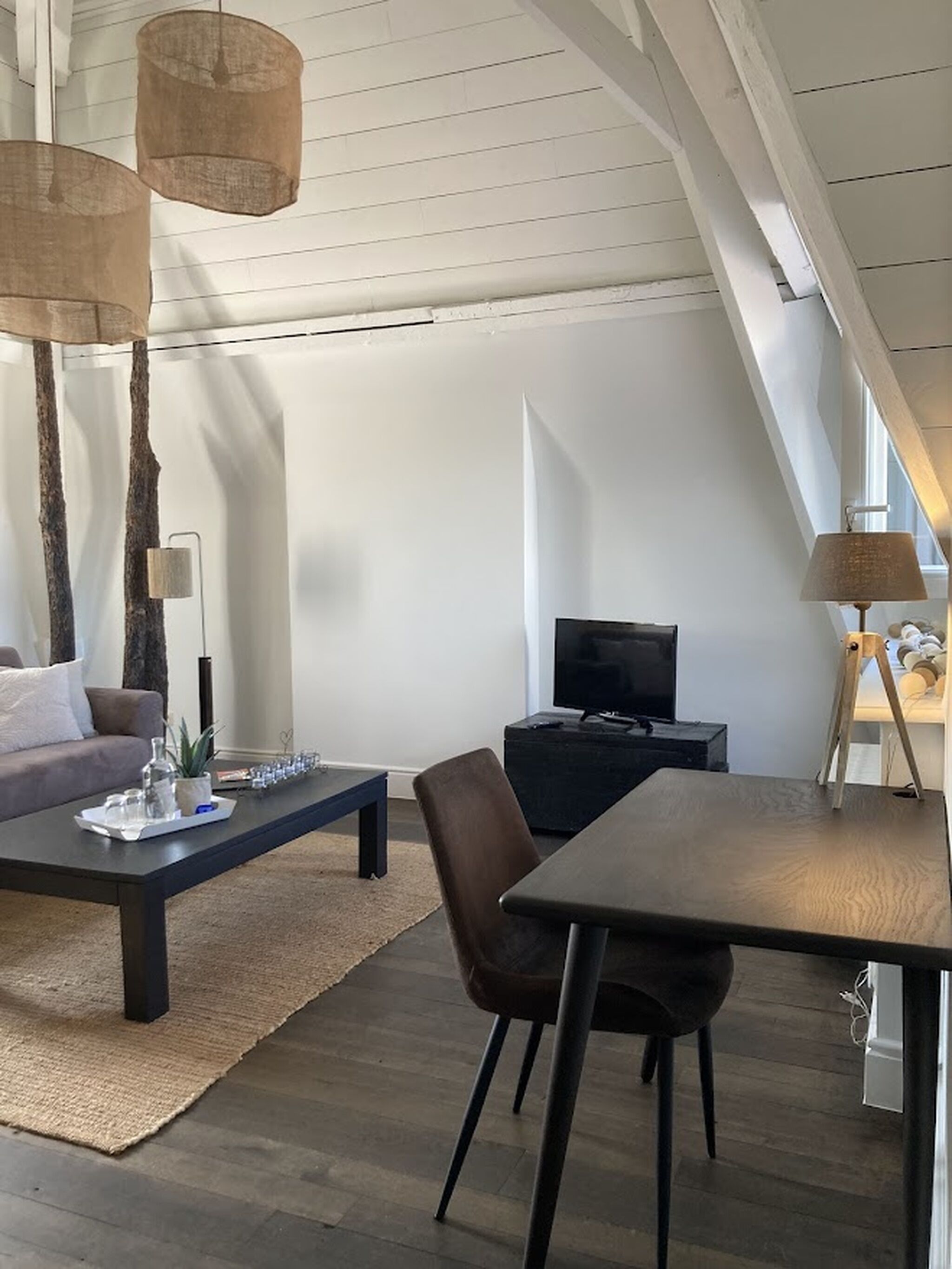 Uma sala de estar moderna com sofá, mesa de centro, televisão e mesa de jantar.