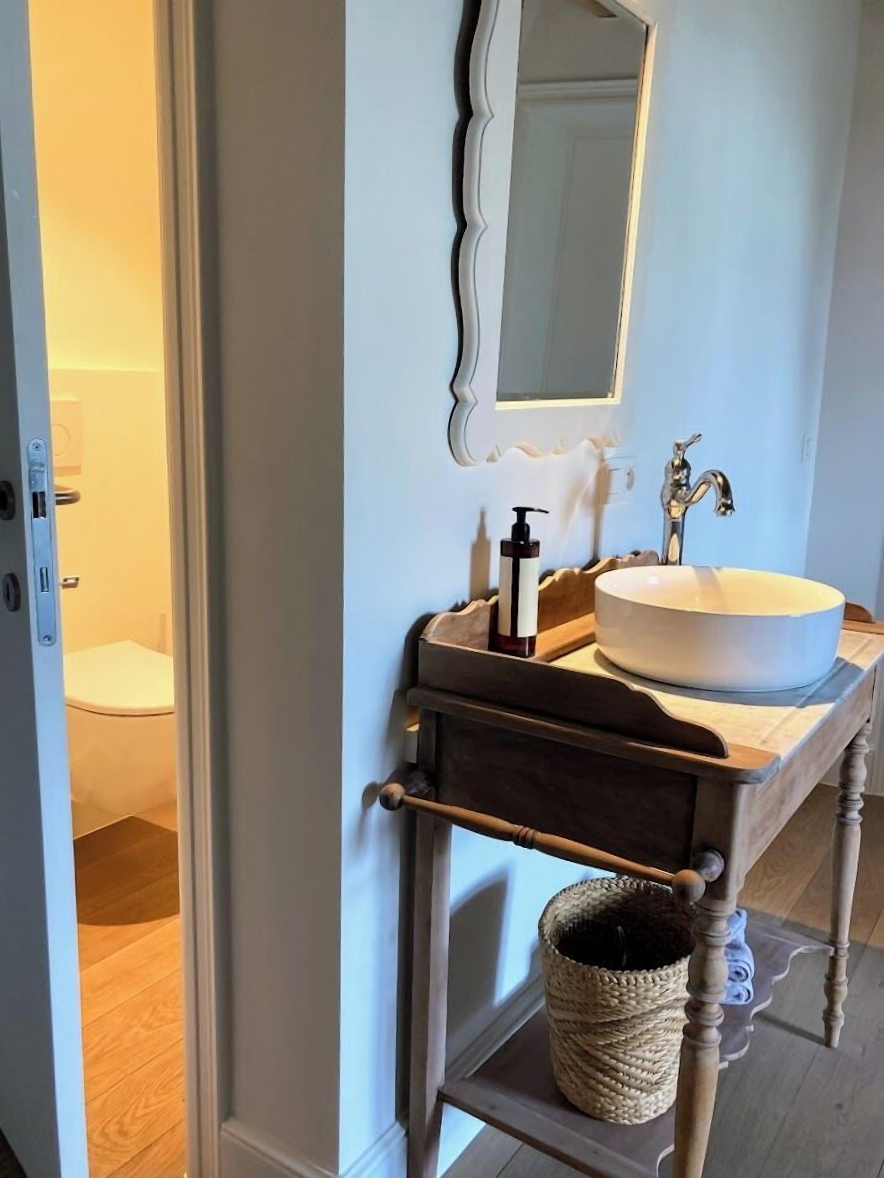 A bathroom with a white sink, a mirror, and a wooden vanity.