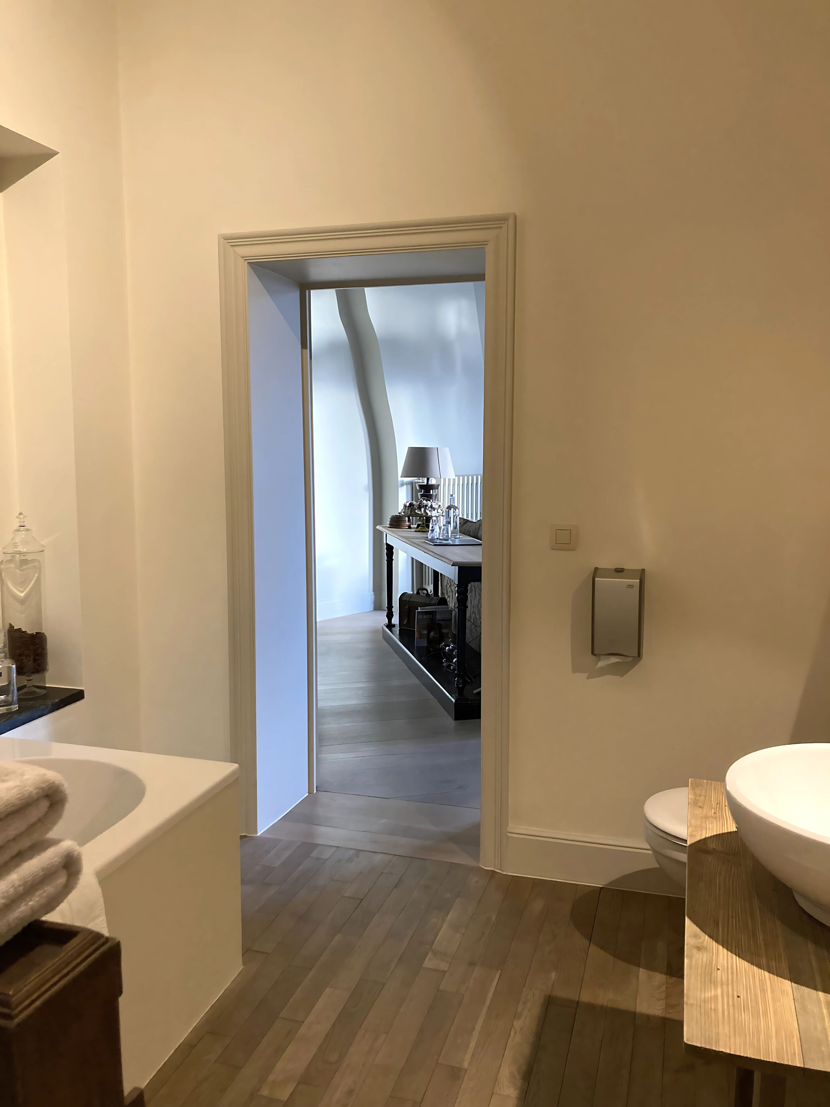 A modern bathroom with a wooden floor, a white sink, and a wooden vanity.