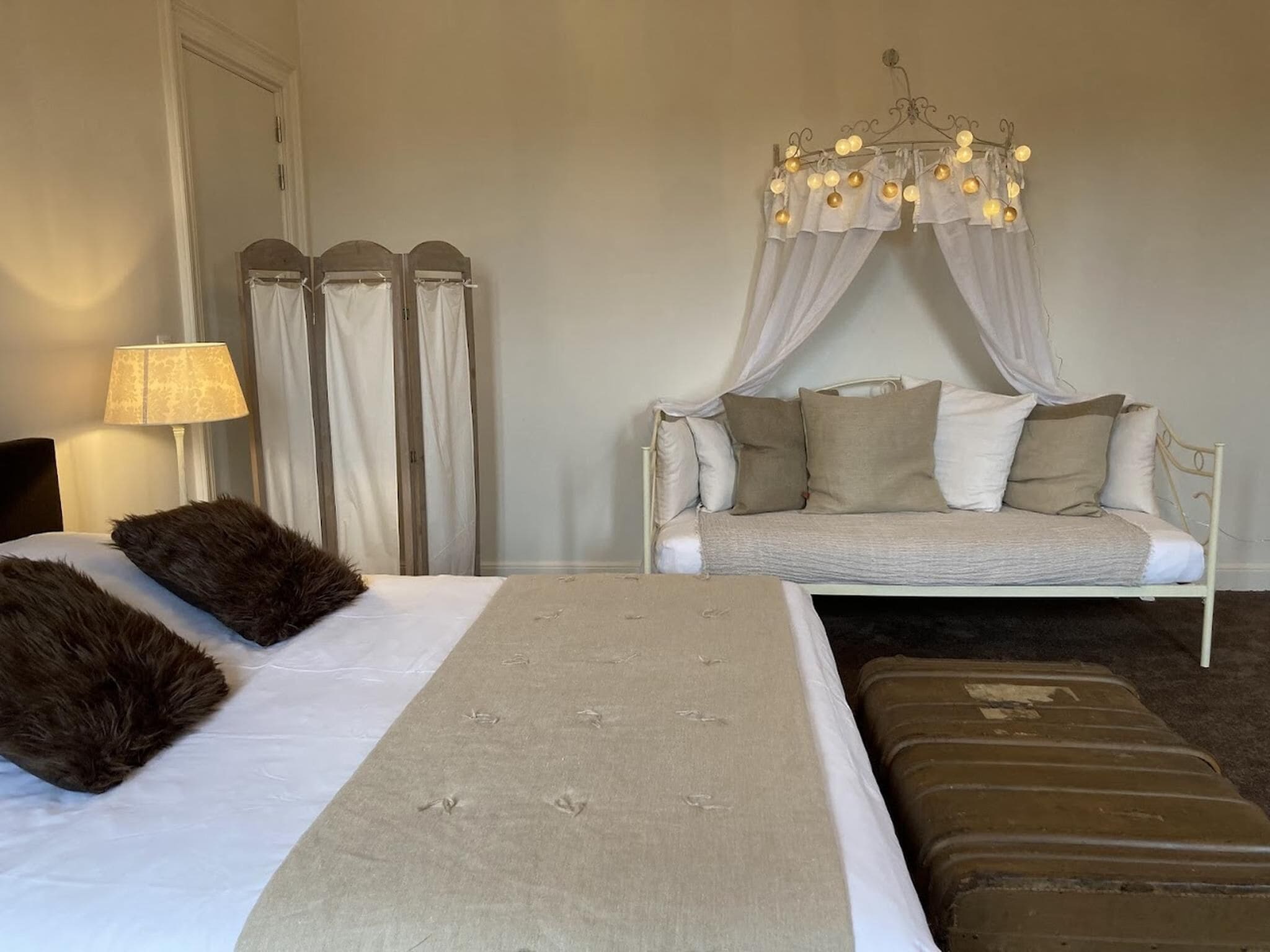A bedroom with a bed, a sofa, a canopy bed, a lamp, and curtains.