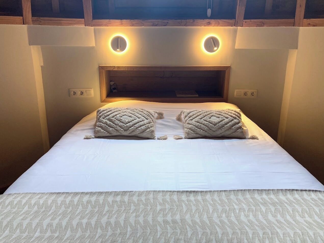 A neatly made bed with two decorative pillows and a patterned bedspread.